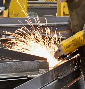 Рабочий производит сварку металлоконструкций на заводе металлоконструкций